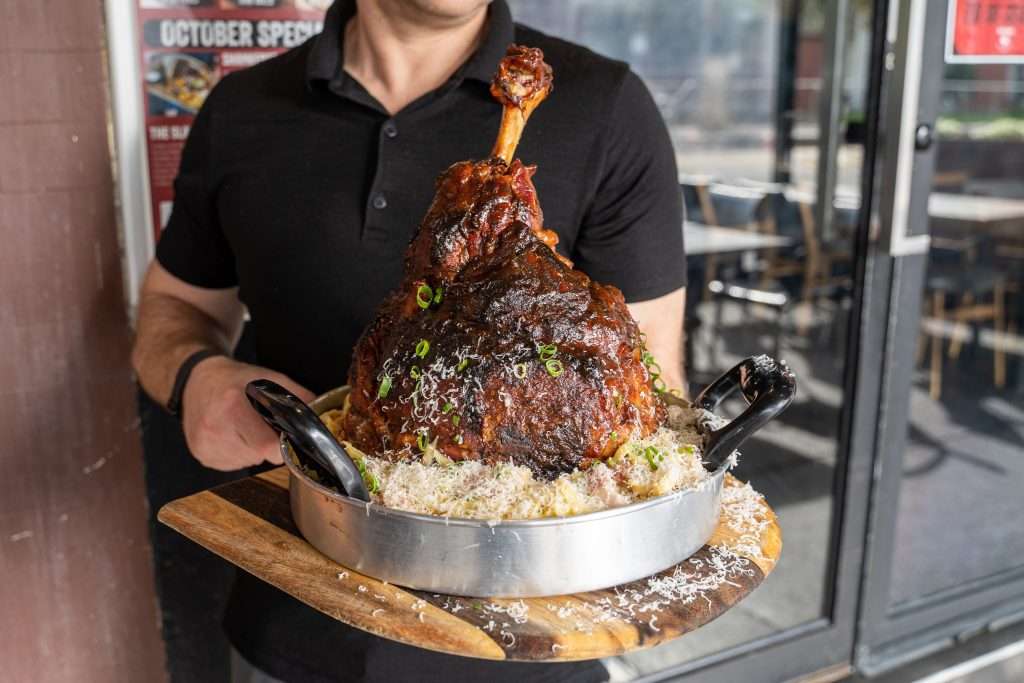 Guest holding the Porkanara pork leg served over pasta